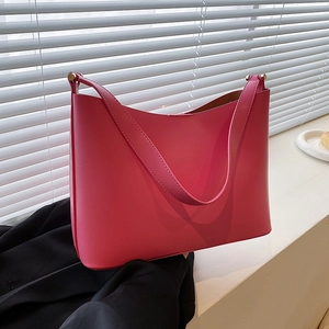 Pink minimalist faux leather tote bag with wide strap on a bright window sill
