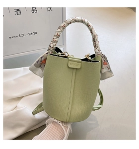 Detail of light green litchi texture bucket bag with silk scarf handle and magnetic closure