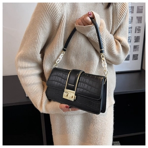 Close-up of black crocodile pattern bag with gold clasp and resin chain strap