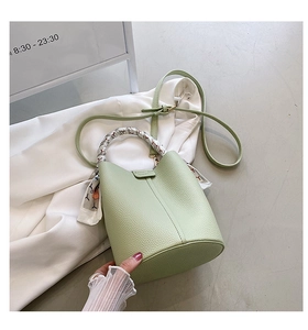 Detail of light green pebble leather bucket bag featuring a silk scarf wrapped handle