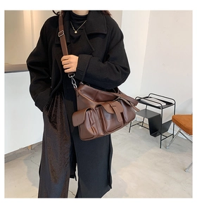 Detail of dark brown leather tote bag featuring multiple pockets and adjustable shoulder strap