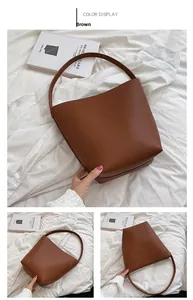 Detail showing brown pebble texture bucket bag with wide fixed handle and flat base