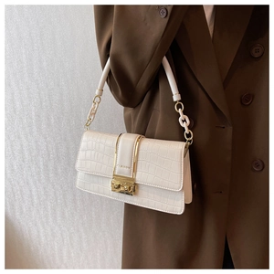 Detail of white crocodile pattern shoulder bag with a gold buckle and chain strap