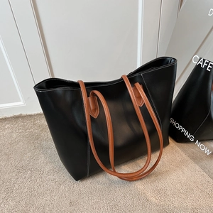 Large black leather tote bag with brown straps and white contrast stitching for daily commute