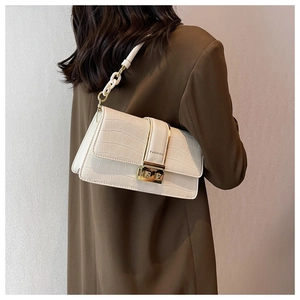 Detail of white crocodile embossed crossbody bag featuring gold buckle and chain strap