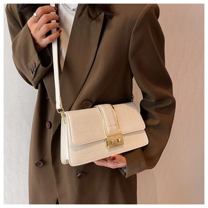 Close-up of beige crocodile pattern crossbody bag with gold fashion buckle clasp