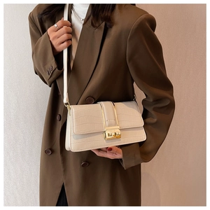 Detail of cream crossbody bag with crocodile texture and gold FASHION metal buckle on a model