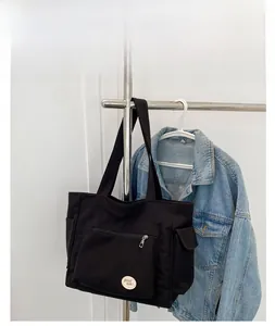 Detail van de zwarte canvas tas met zijvak en 'good luck' patch aan een hanger