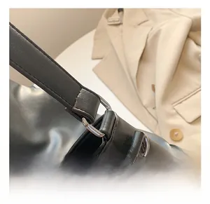 Close-up of black leather shoulder strap with silver D-ring buckle on a tote bag