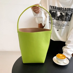 Fashionable lime green bucket bag with lychee texture held in a lifestyle setting