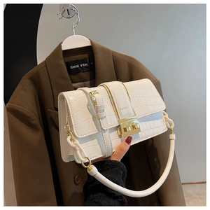 Detail of white crocodile pattern leather handbag with gold square buckle and chic handle
