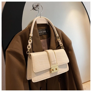 Detail of off-white crocodile pattern handbag with gold fashion clasp and mixed chain strap