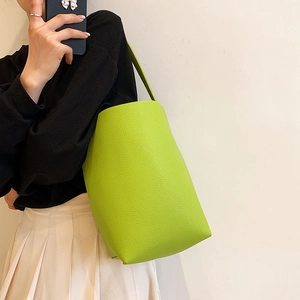 Minimalist lime green bucket bag in pebble leather worn by model for daily fashion look