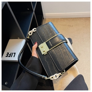 Detail of black crocodile pattern crossbody bag with gold buckle and bicolor strap