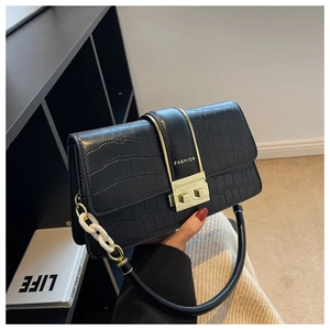 Close-up of black crocodile pattern crossbody bag with gold lock and white chain detail