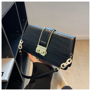 Detail of black crocodile texture bag with gold FASHION buckle and chain handle