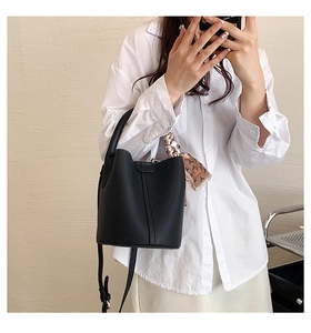 Detail of black lychee leather bucket bag with decorative silk scarf on the handle