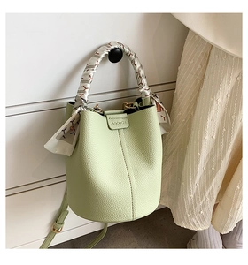 Detail of pistachio green leather bucket bag with silk scarf wrapped top handle and strap