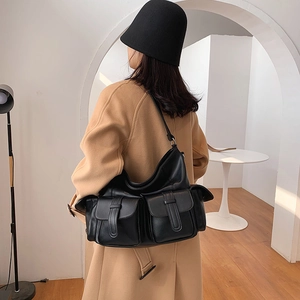 Minimalist black large capacity leather tote bag with dual front pockets worn by a model