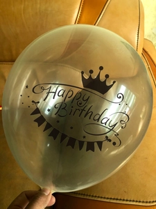 Détail macro du ballon en latex transparent avec couronne noire et texte Happy Birthday