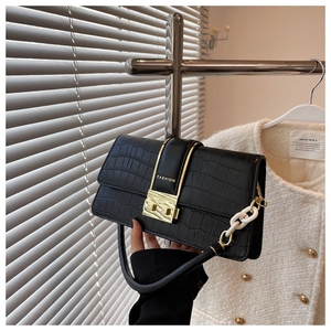 Close-up of black crocodile pattern crossbody bag with gold buckle and white resin chain