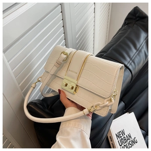 Detail of white crocodile pattern leather bag featuring gold clasp and decorative chain