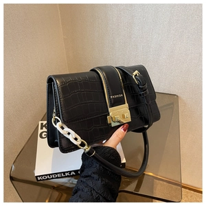 Close-up of black crocodile pattern leather handbag with gold buckle and fashion text