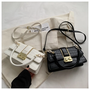 Detail of crocodile pattern leather cross-body bags with golden metal clasps and strap