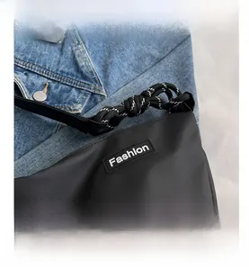 Detail of black oxford fabric crossbody bag showing the Fashion label and knotted rope detail