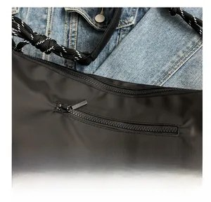 Detail of smooth metal zipper on black oxford fabric bag over denim background