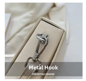Detail shot of silver metal hook hardware on cream leather chain crossbody bag