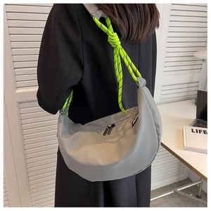 Detail of grey crossbody bag featuring a vibrant neon green braided rope shoulder strap