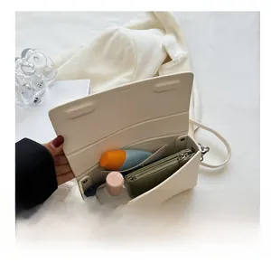 Interior view of off-white leather crossbody bag showing storage for cosmetics and wallet