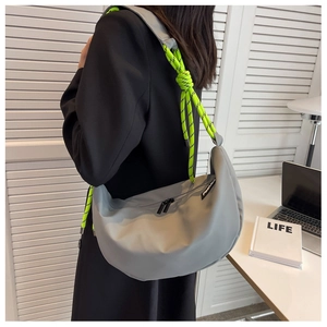Detail of grey half-moon nylon bag with vibrant neon green rope strap and black zipper