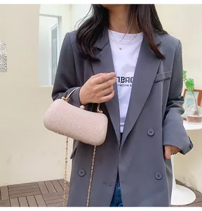 Détail d'une pochette tissée rose avec poignée dorée, fermoir perle et bandoulière