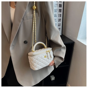 Detail of white quilted mini vanity bag with golden chain strap and adjustable ball buckle