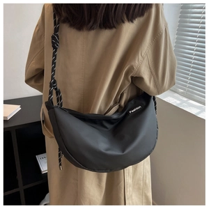 Back view of black crescent oxford crossbody bag with woven knot strap on a model