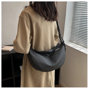 Close-up of black crescent oxford cloth crossbody bag with woven rope strap and fashion patch