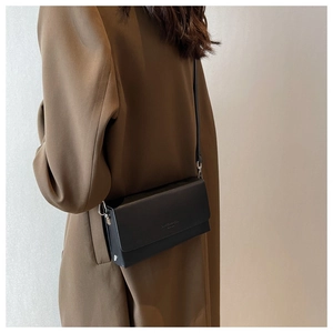 Detail view of black rectangular crossbody bag with silver hardware and narrow shoulder strap