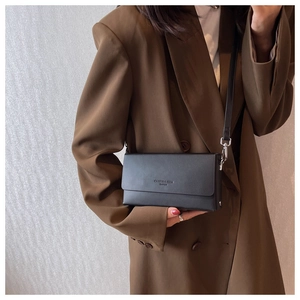 Close-up of minimalist black matte leather crossbody bag with elegant chain strap detail