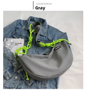 Detail of grey Oxford crossbody bag with neon green rope strap and Fashion label