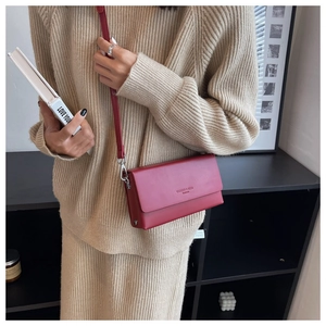 Dark red crossbody square bag with gold lettering shown on a beige knit sweater