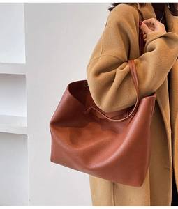 Detail of tan pebble-leather tote bag showing textured surface and slender shoulder straps