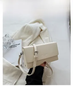 Detail of a minimalist cream white leather crossbody bag with adjustable silver buckle strap