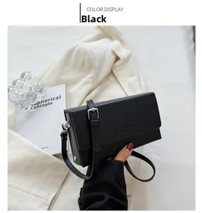 Detail of a black crossbody bag with adjustable silver buckle strap on a minimal background