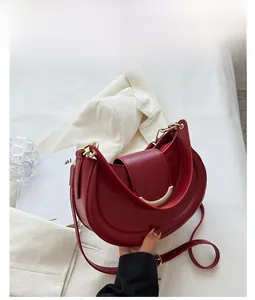 Detailed close-up of wine red crescent bag with elegant gold clasp and smooth texture