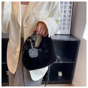 Detail of plush black handbag featuring gold chain and 'You deserve better' round tag