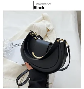Detail of black crescent shoulder bag featuring a matte finish and golden metal buckle