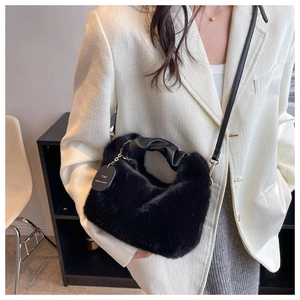 Detail of plush black faux fur handbag featuring gathered PU handle and metal chain tag