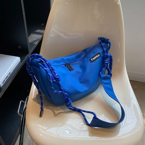 Blue nylon crossbody bag with braided rope strap on a white chair in a minimalist room
